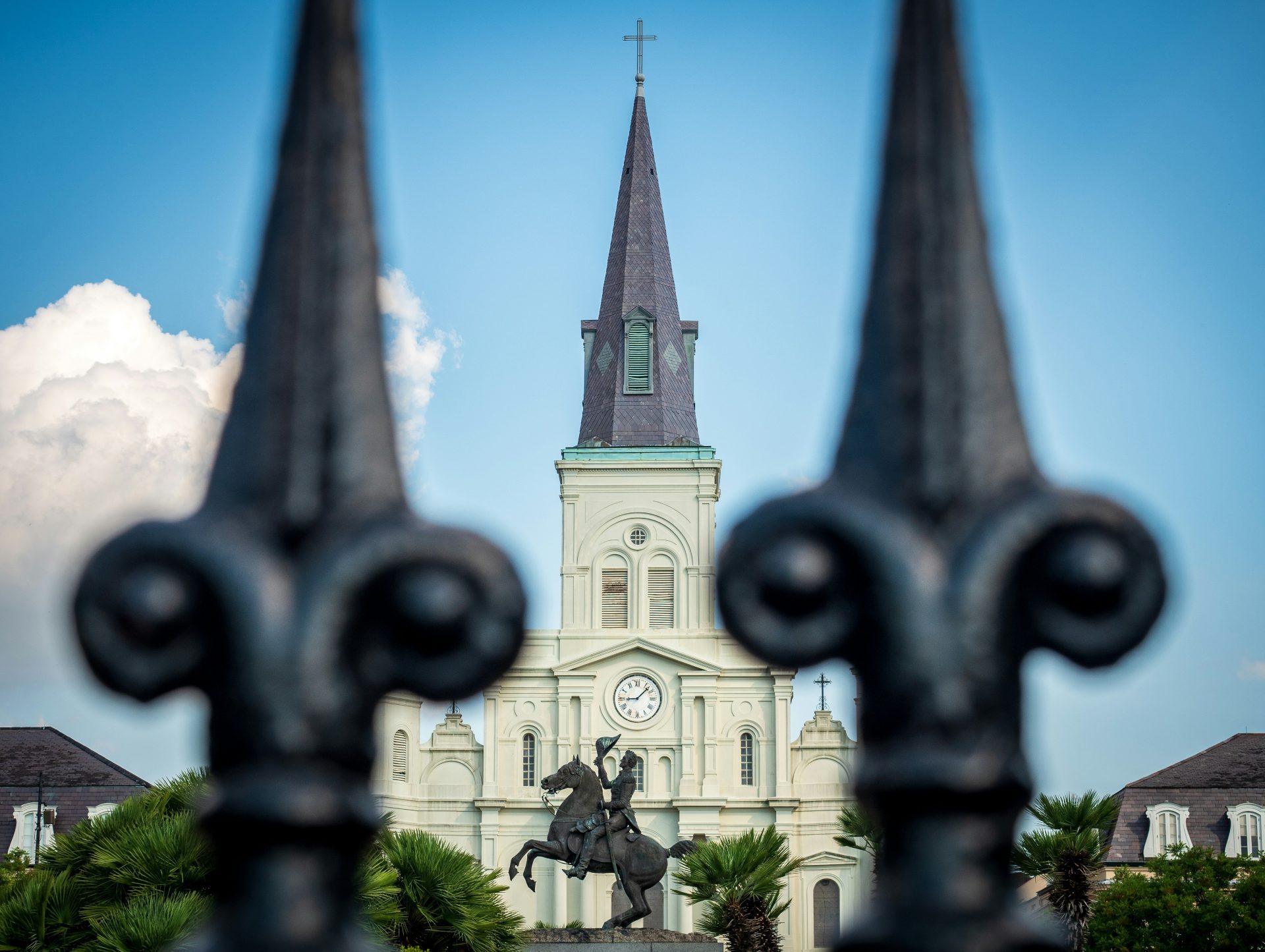 A church steeple framed by black wrought iron fence.
